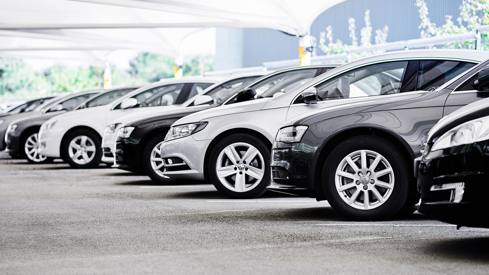 Find the right vehicle or asset finance... A fleet of silver, black and white cars lined up in a showroom, ready to be hired or leased